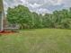 Large backyard featuring a deck and an expansive green lawn surrounded by mature trees at 4601 Lindsey Dr, Powder Springs, GA 30127