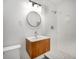 Modern bathroom with wood vanity, round mirror, white tiled shower, and a stylish design at 4601 Lindsey Dr, Powder Springs, GA 30127