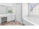 Bright bathroom with double vanity, white cabinets, large mirror, a window and large tub at 7000 Foxberry Ln, Roswell, GA 30075