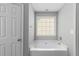 A modern bathroom with a large white tub, neutral paint and a window at 7000 Foxberry Ln, Roswell, GA 30075