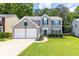 Charming two-story home featuring a manicured lawn, complemented by an attached two-car garage and lush landscaping at 7000 Foxberry Ln, Roswell, GA 30075