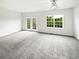 Bright living room with plush carpeting, a ceiling fan, and access to the outdoors through glass doors at 2438 Suwanee Pointe Dr, Lawrenceville, GA 30043