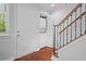 Hallway with wood-look flooring, stairs with wrought iron railing, laundry closet, and door to exterior at 31 Country Place Ct, Alpharetta, GA 30005