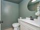 Stylish powder room with green walls, a round mirror, and a white vanity at 3375 Rivendell Ct, Roswell, GA 30075