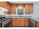 A well-lit kitchen with wooden cabinetry, granite counters, stainless steel appliances, and wood-look floors at 3997 Paloverde Nw Dr, Kennesaw, GA 30144