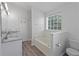 Bright bathroom featuring double sink vanity, tub, and window allowing natural light at 1644 Royal Ives Dr, Lawrenceville, GA 30045
