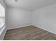 A minimalist bedroom featuring wood-look floors, a window with blinds, and freshly painted white walls at 1644 Royal Ives Dr, Lawrenceville, GA 30045