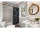 Bright bathroom featuring a shower-tub combination and pedestal sink with decorative round mirror at 1772 Ridgewood Ne Dr, Atlanta, GA 30307