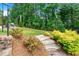 Landscaped backyard featuring an outdoor kitchen and scenic greenery at 310 Braeden Way, Alpharetta, GA 30009