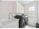 Bright laundry room with modern appliances, a sink and white cabinets for efficient chores at 310 Braeden Way, Alpharetta, GA 30009