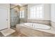 Modern main bathroom with a glass-enclosed shower and separate soaking tub with neutral tile at 310 Braeden Way, Alpharetta, GA 30009