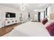 Opulent main bedroom with statement chandelier, hardwood floors, and a sitting area at 310 Braeden Way, Alpharetta, GA 30009