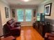 Comfortable living room with a red leather sofa, TV, large windows, and hardwood floors, ideal for relaxation at 3545 Manchester Dr, Lawrenceville, GA 30044