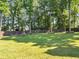 A spacious backyard with a well-maintained lawn, surrounded by lush trees and fencing for privacy at 70 Maplewood Ln, Acworth, GA 30101