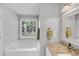 Well-lit bathroom featuring a soaking tub, large window, and granite countertop vanity at 70 Maplewood Ln, Acworth, GA 30101