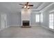 Spacious living room featuring a fireplace, large windows, ceiling fan and neutral colored carpet at 1037 Windermere Xing, Cumming, GA 30041
