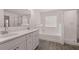 Elegant bathroom featuring double sink vanity, glass shower, and a large soaking tub under a window at 1821 Lacebark Elm Way, Lawrenceville, GA 30045