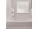 Close-up of a pristine white bathtub with a chrome faucet and white tiled surround under a frosted window at 1821 Lacebark Elm Way, Lawrenceville, GA 30045