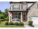 Welcoming front porch of a two-story home, adorned with rocking chairs and a 'Welcome' sign, set against a brick facade at 521 Andes Ln, Canton, GA 30114