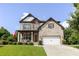 Charming two-story home featuring a covered porch with rocking chairs, brick and stone facade, and manicured lawn at 521 Andes Ln, Canton, GA 30114