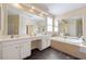 Bright bathroom featuring double sinks, a large mirror, tiled flooring, and a soaking tub at 801 Windsor Rdg, Canton, GA 30115