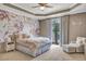 This bedroom has a floral accent wall, a modern ceiling fan, and a light colored bed and chair at 4317 Oglethorpe Nw Loop, Acworth, GA 30101