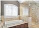 This main bathroom features a window overlooking the tub and a glass-enclosed shower with multiple shower heads at 4317 Oglethorpe Nw Loop, Acworth, GA 30101