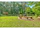 Large backyard with fire pit, grass, mature trees, and a pond with dock for outdoor entertaining at 3122 Harmony Rd, Temple, GA 30179