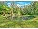 Picturesque pond surrounded by lush greenery with dock, enhancing the backyard's natural beauty at 3122 Harmony Rd, Temple, GA 30179
