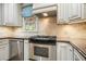 Updated kitchen with stainless steel oven, stone tile backsplash, granite counters, and white cabinetry at 4138 Glenlake Nw Ter, Kennesaw, GA 30144