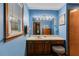 This blue bathroom has wood vanity, toilet, and mirror above the sink at 220 Gamble Dr, Carrollton, GA 30116