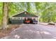 A home with dark siding and a carport displays two parked trucks in the driveway beneath the shade of tall trees at 220 Gamble Dr, Carrollton, GA 30116