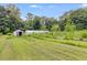The backyard of the house features a well-maintained lawn, outbuildings, and a greenhouse, surrounded by trees at 220 Gamble Dr, Carrollton, GA 30116