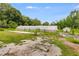 An outdoor greenhouse sits on a grassy and gravel lot, with a shed in the background, surrounded by lush green trees at 220 Gamble Dr, Carrollton, GA 30116