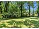 Sprawling backyard with mature trees casting shadows on a grassy lawn at 2532 Millbrook Dr, Snellville, GA 30078