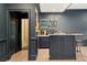 A stylish home bar features a mirrored backsplash, open shelving, and sophisticated dark blue cabinetry at 4435 Pemberton Cv, Johns Creek, GA 30022