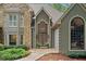 Elegant stone and stucco exterior with arched windows and a grand front door, surrounded by lush landscaping at 4435 Pemberton Cv, Johns Creek, GA 30022