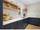 Modern kitchen with white subway tile, open wood shelving, and custom blue cabinetry with bronze hardware at 4435 Pemberton Cv, Johns Creek, GA 30022