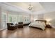 Bright main bedroom features hardwood floors, tray ceilings, a seating area, and a decorative chandelier at 4435 Pemberton Cv, Johns Creek, GA 30022