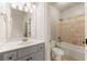 Well-lit bathroom featuring a bathtub with tiled surround, white toilet, and gray vanity with ample lighting at 2539 Sagebrush Trl, Buford, GA 30519
