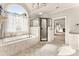 Well-lit bathroom featuring a tub under an arched window and a walk-in shower at 2539 Sagebrush Trl, Buford, GA 30519
