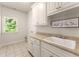 Bright laundry room with white cabinetry, utility sink, and a window providing natural light at 2539 Sagebrush Trl, Buford, GA 30519