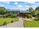 A spacious backyard featuring lush lawn, mature trees, a stone pathway, and a covered patio at 110 Village Ct, Woodstock, GA 30188