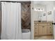 Updated bathroom featuring a tub with shower, wooden accent wall, granite vanity and beige cabinets at 110 Village Ct, Woodstock, GA 30188