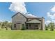 Backyard with a covered porch, lush lawn, mature trees, and a brick exterior, ideal for outdoor living at 1405 Rainey Way, Hampton, GA 30228