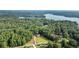 An aerial view of the home nestled in a lush forest with a lake in the background at 6685 Driskell Rd, Cumming, GA 30041