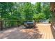Wooden deck featuring an outdoor dining area, surrounded by a dark metal railing and lush trees at 6685 Driskell Rd, Cumming, GA 30041