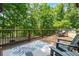 Wide shot of a spacious wood deck surrounded by green trees and outdoor seating, with a leafy rug at 6685 Driskell Rd, Cumming, GA 30041