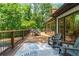 Spacious wood deck featuring outdoor seating, dining table, and lush green trees in the background at 6685 Driskell Rd, Cumming, GA 30041