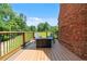 Wooden deck with a fire pit and outdoor seating, next to an exposed brick wall with a view of green trees at 6685 Driskell Rd, Cumming, GA 30041
